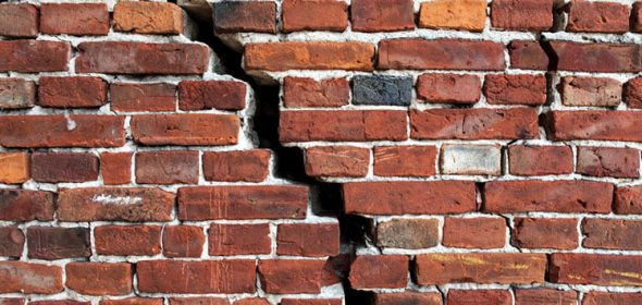 Huge vertical crack on a brick wall.