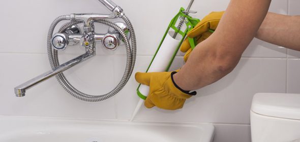 Man applying caulk to a bathtub.
