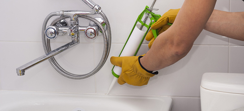 Man applying caulk to a bathtub.